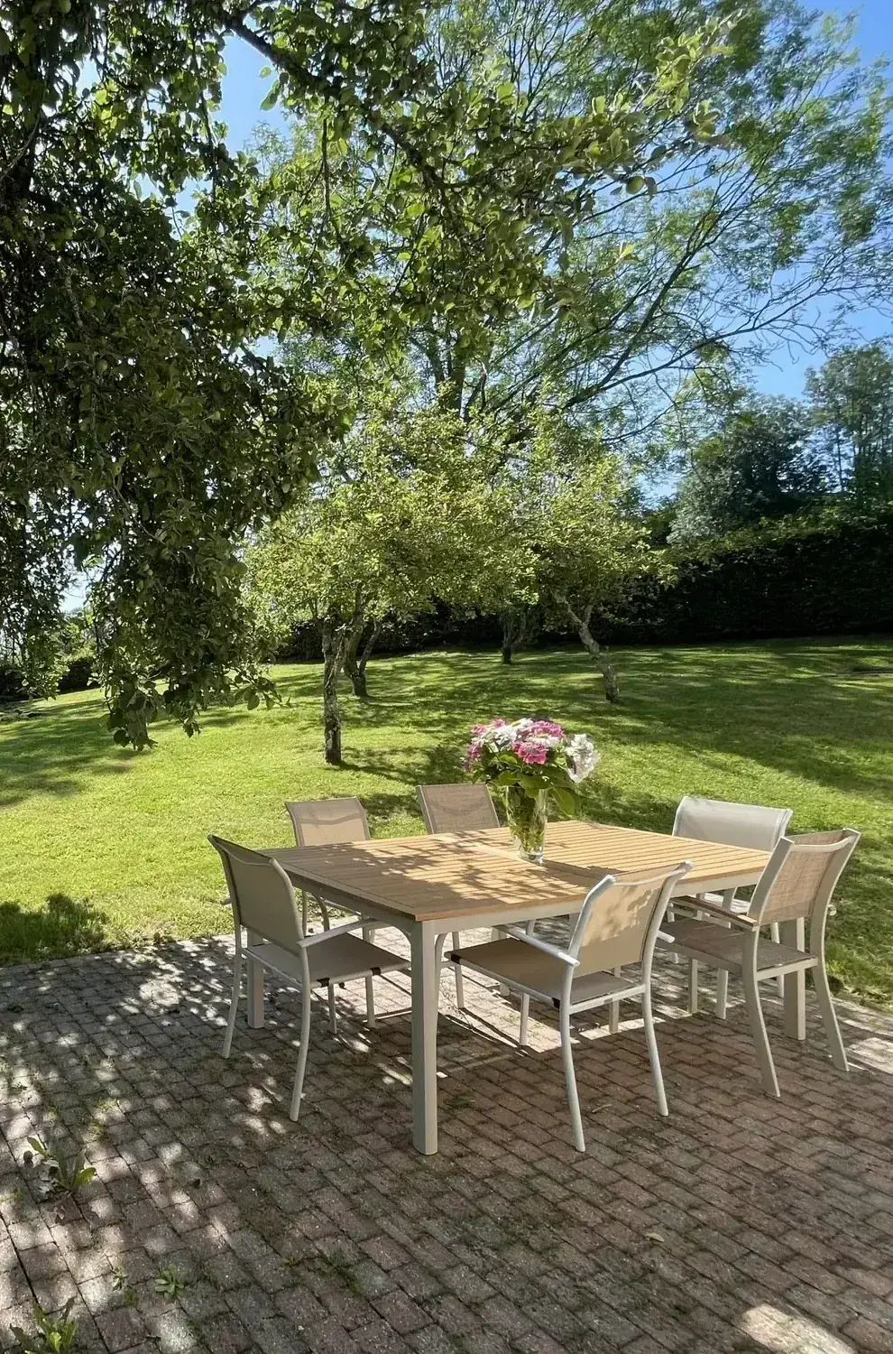 La table du jardin de Reinette Grise, dressée sous le pommier, face à la pelouse et aux prés