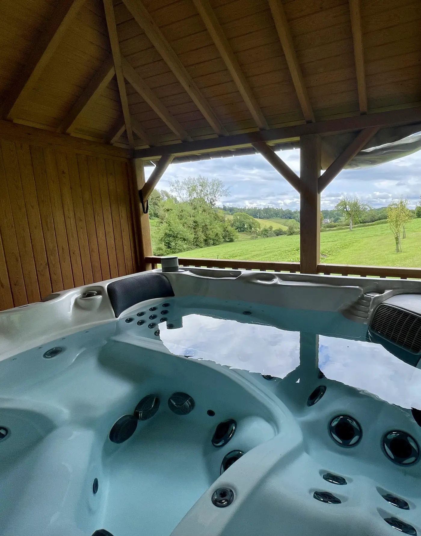 Le jacuzzi du Hameau sous la charpente de son kiosque, ouvert sur les prés