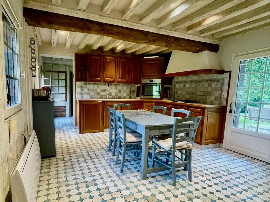 La cuisine de Reinette Grise, la table et ses chaises bleues sous les poutres