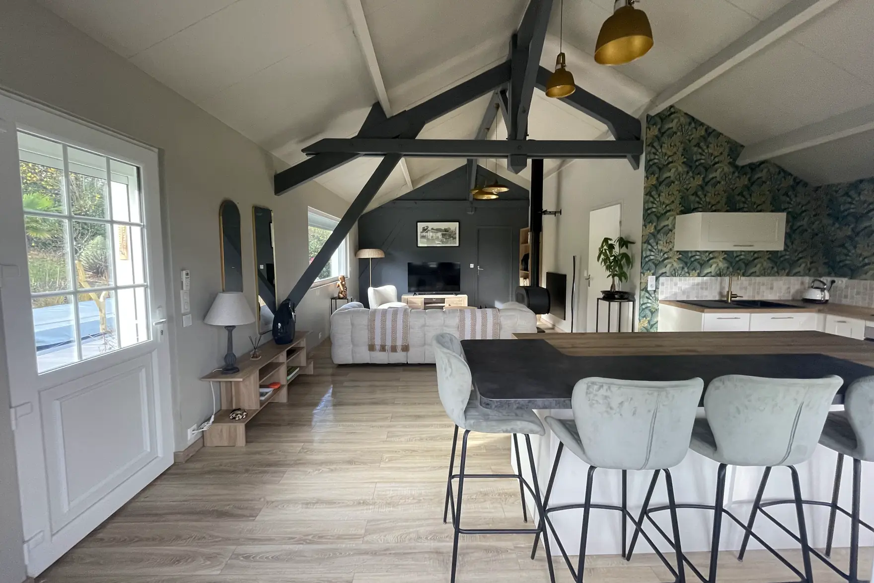 Le séjour du Chalet Normand sous sa charpente peinte, la cuisine ouverte et son grand bar